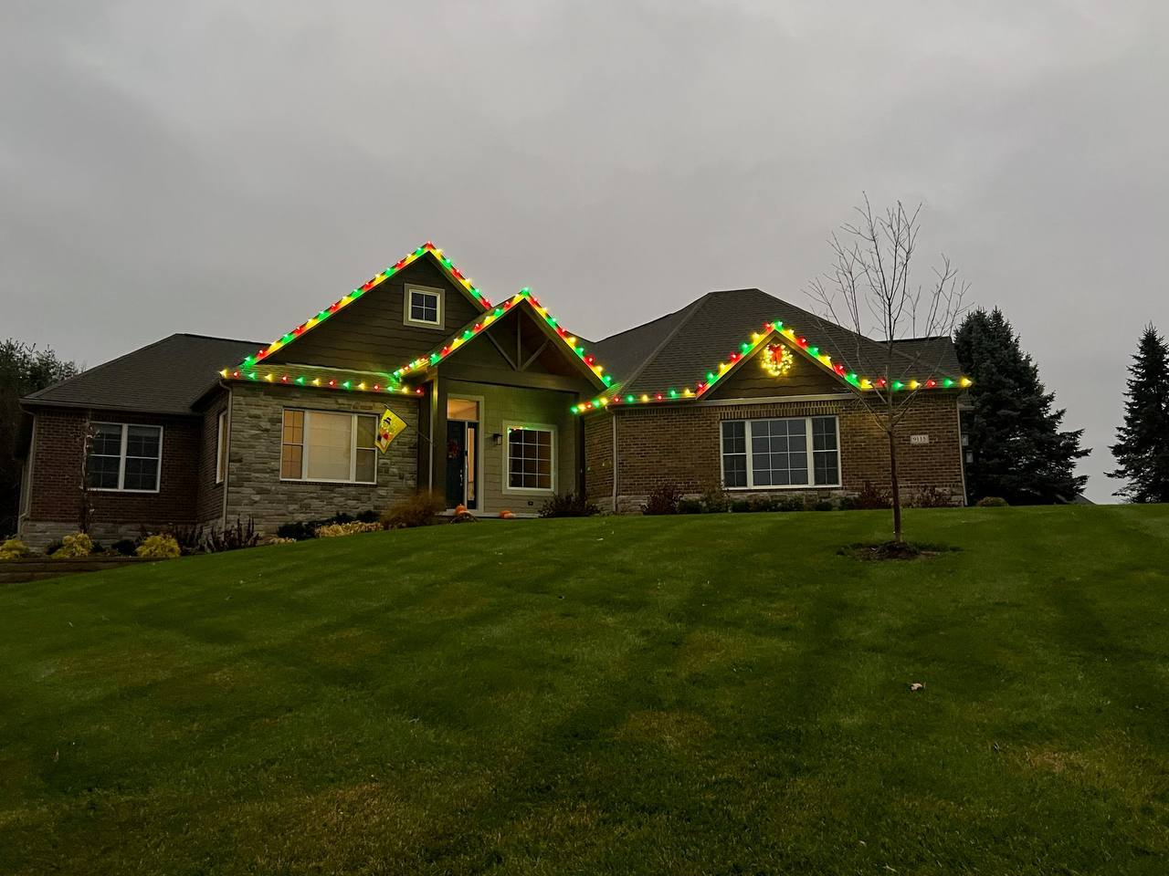Warm white Christmas lights installed along the roofline of a large home