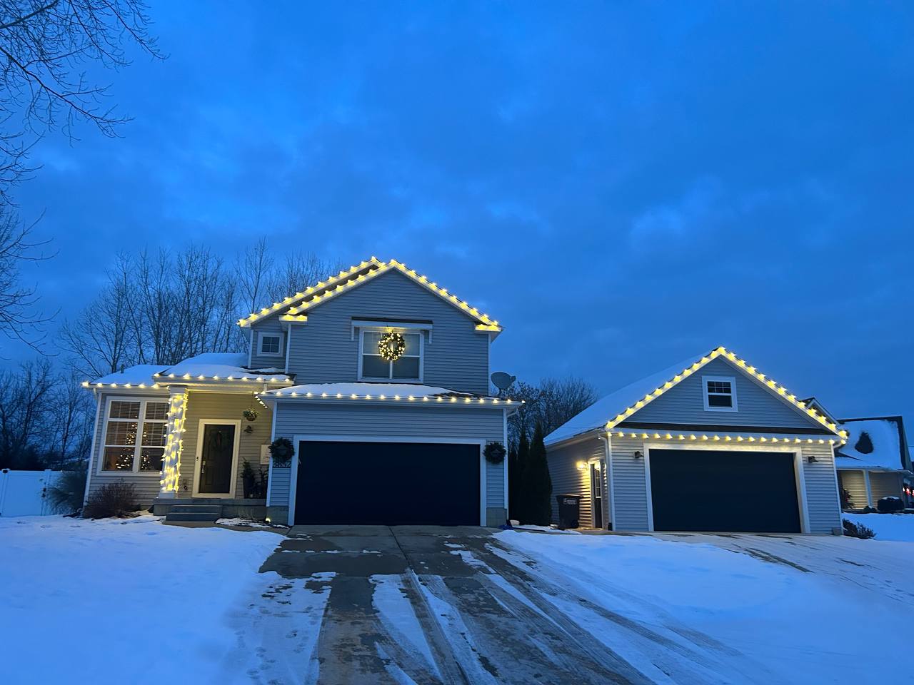 Red and green Christmas lights outlining the roof of a brick home