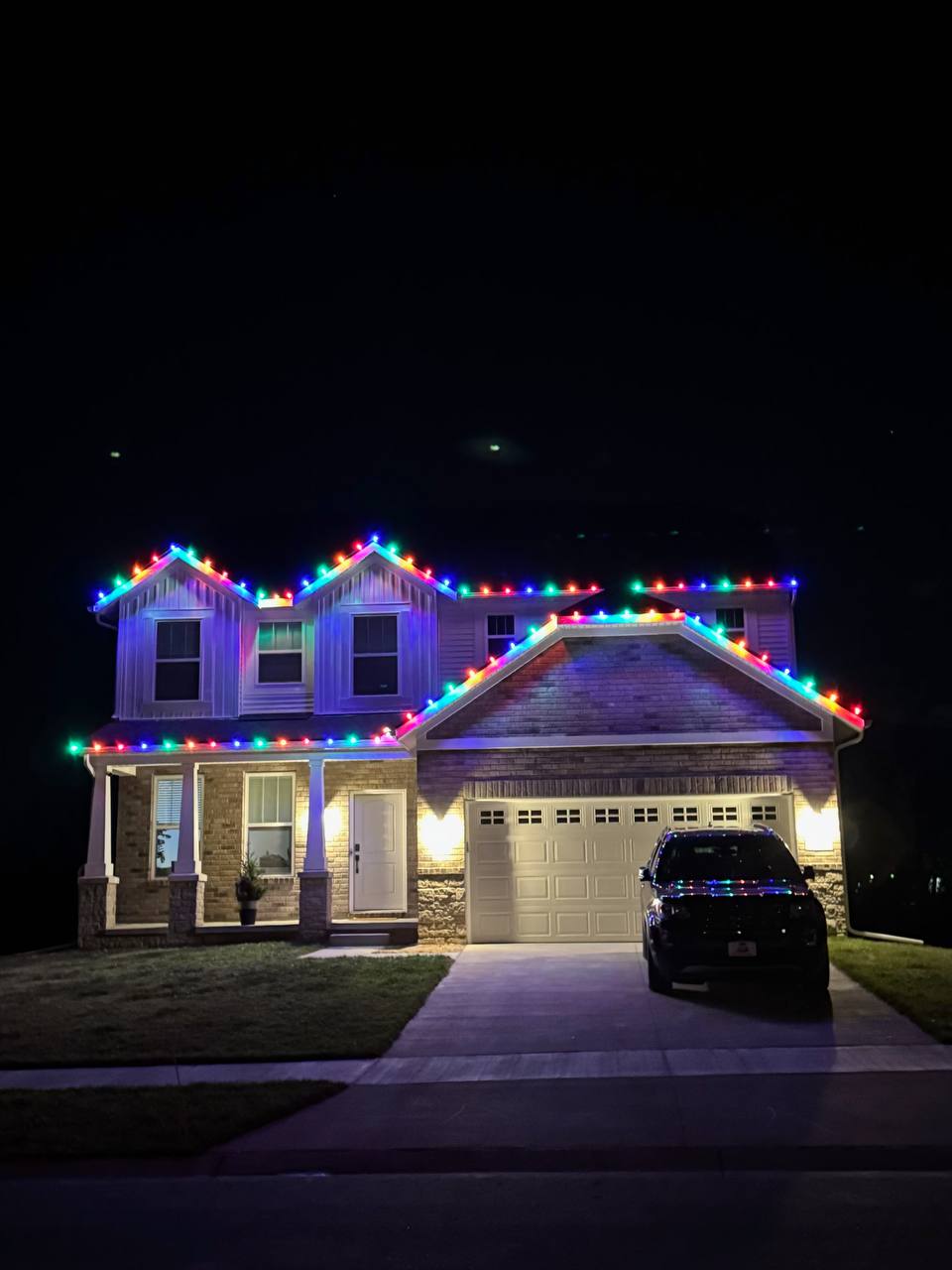 Warm white holiday lights decorating a home with a holiday installation sign