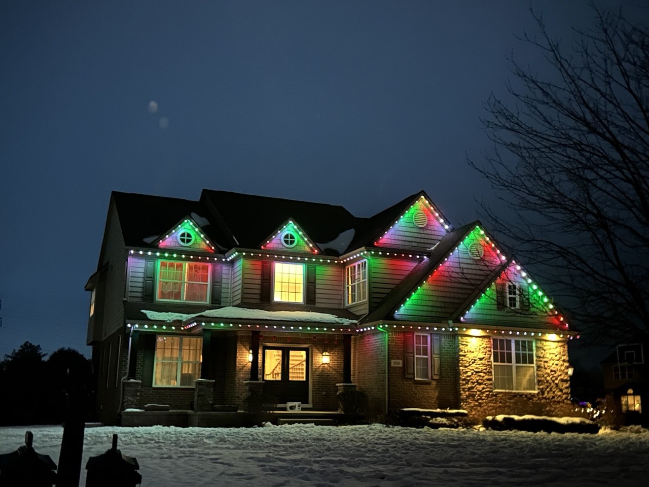 Permanent holiday lighting installed on a home in classic Christmas red and green colors