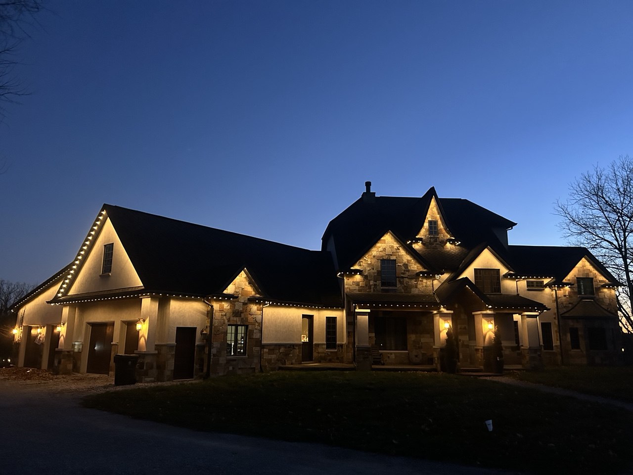 Warm white permanent lighting illuminating the roofline of a home on a winter evening